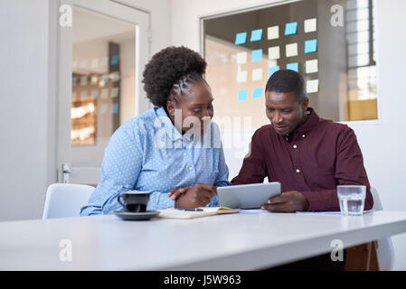 Young African work colleagues using a tablet in an office Stock Photo