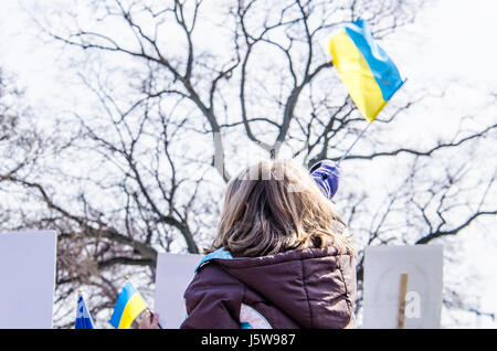 Washington DC, USA - March 6, 2014: People during protest by White House with girl sitting on man's shoulders waving Ukrainian flag Stock Photo