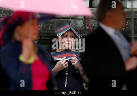 A guest shelters from rain as Queen Elizabeth II attends a ceremony to present new colours to the 1st Battalion and F Company Scots Guards at Buckingham Palace in London. Stock Photo
