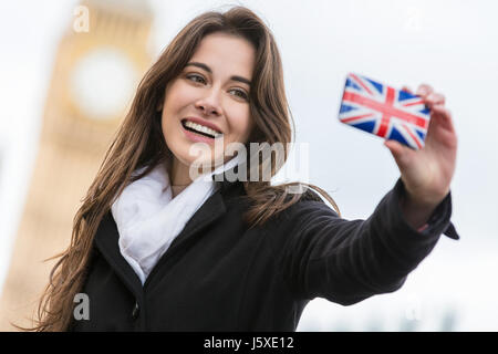 Girl or young woman tourist on vacation taking a selfie photograph by Big Ben with Union Jack cell phone, London, England, Great Britain Stock Photo