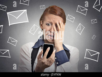 Upset stressed woman holding cellphone disgusted shocked with message she received isolated grey background. Funny looking human face expression emoti