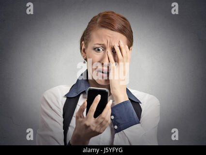 Upset stressed woman holding cellphone disgusted shocked with message she received isolated grey background. Funny looking human face expression emoti