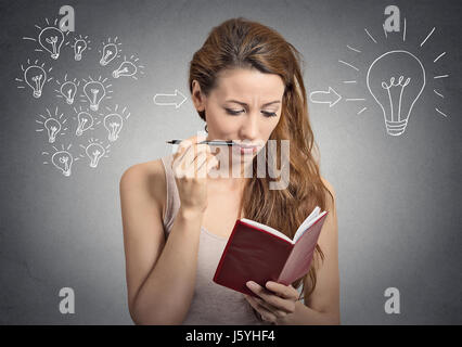 portrait beautiful girl thinking planning writing down notes isolated on grey wall background Stock Photo