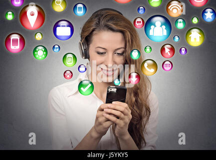 communication technology mobile high tech concept. Young woman using texting listening to music on smartphone with social media application symbols ic Stock Photo