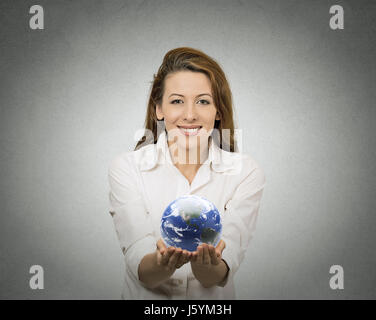 Happy woman holding showing glowing earth globe in her hands on grey wall background. Earth image provided by Nasa. Positive face expressions, emotion Stock Photo