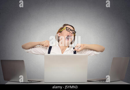 Portrait sleepy yawning business woman with wide open mouth eyes closed looking bored sitting at desk with computers isolated office grey wall backgro Stock Photo