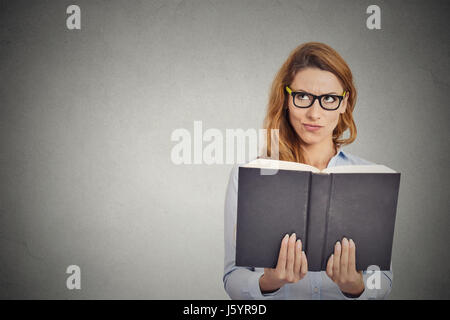 Closeup clever woman reading book having thought isolated on grey wall background. Human face expression Stock Photo