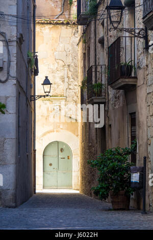 A painted metal arch dor at the end of a narrow lane way in the old quarter of Girona, Spain. Stock Photo