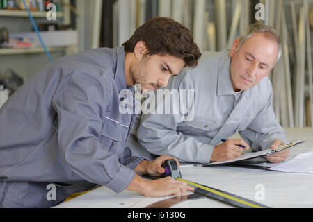 Man using tape measure, older man watching Stock Photo