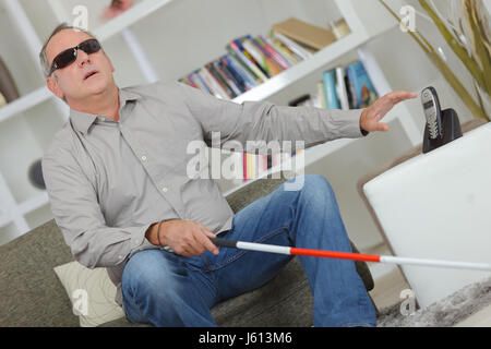 Blind and deaf man using stick at home Stock Photo