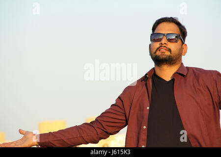 Young Indian man with goggles and outstretched hands as a welcome gesture Stock Photo