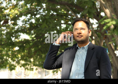 Confident young Indian man in suit talking on his mobile Stock Photo