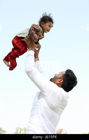 Young Indian father playing with toddler by throwing him in the air Stock Photo