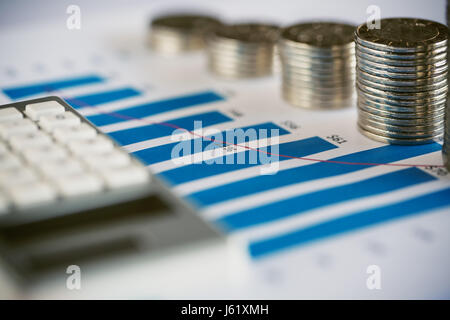 Stack of coins with bar chart and calculator Stock Photo
