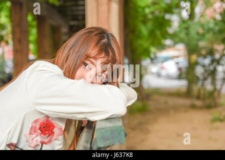 Young asian woman sitting in chair outdoor and looking at camera Stock Photo