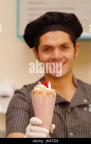 Handsome man with a cheff hat poiting in from of him a milkshake Stock Photo