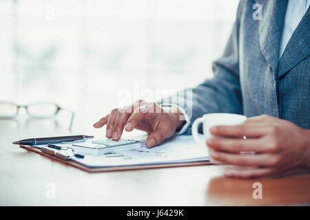 Businesswoman using calculator to analyze business chart Stock Photo