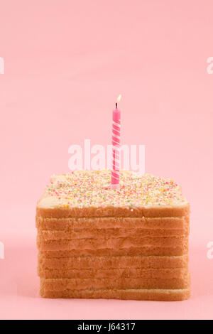 a quirky icing birthday bread covered with sprinkles on pink background Stock Photo