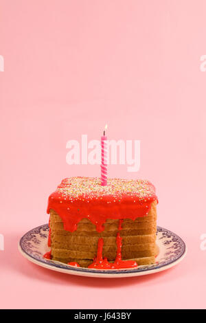 a quirky icing birthday bread covered with sprinkles and red coulis on pink background Stock Photo