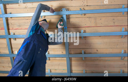 man assembles profile metal frame for plasterboard ceilings Stock Photo