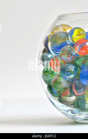 glass marbles in transparent bowl on white table Stock Photo