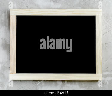 Blank black chalkboard with wooden frame on concrete background. Stock Photo