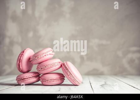 Stack of Raspberry pastel pink Macarons or Macaroons over grey concrete wall background Stock Photo