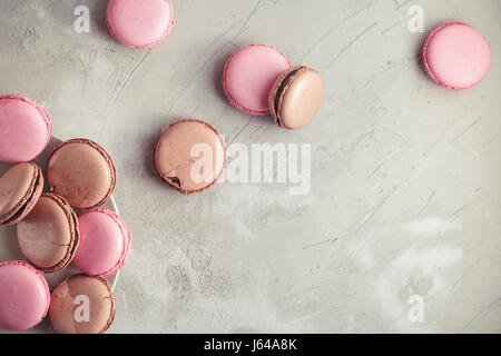 Raspberry and Chocolate pastel colored Macarons or Macaroons over concrete stone background Stock Photo