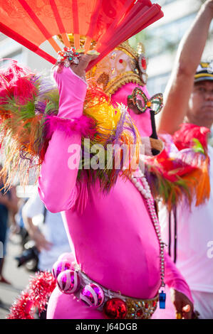 RIO DE JANEIRO - FEBRUARY 11, 2017: A figure in flamboyant pink costume celebrates at a street party during the city's carnival celebrations.
