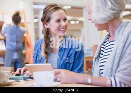Smiling mother and daughter using digital tablet in cafe Stock Photo