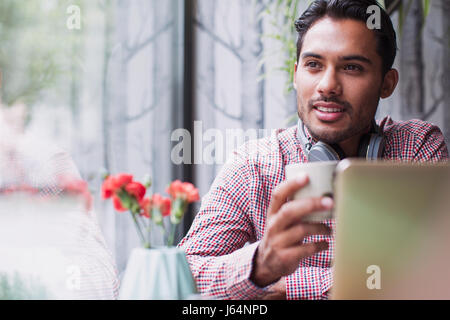Pensive man drinking coffee at laptop in cafe window Stock Photo
