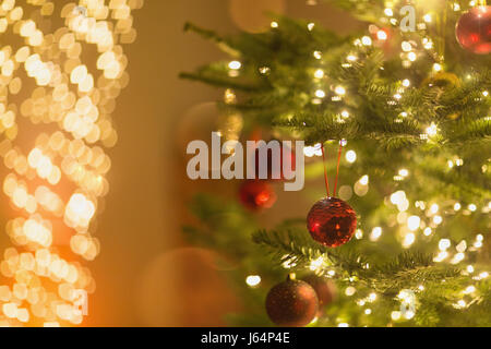 Red ornaments hanging from Christmas tree with string lights Stock Photo
