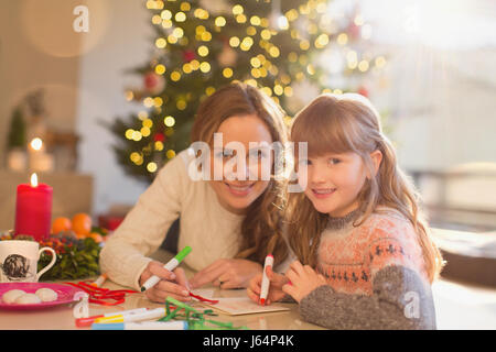 Portrait smiling mother and daughter coloring with markers in Christmas living room Stock Photo