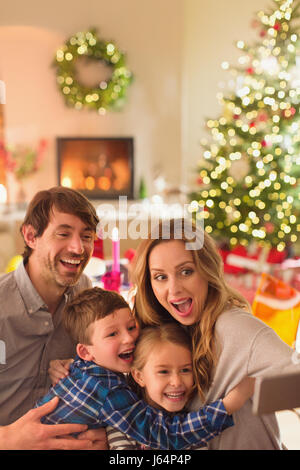 Silly family taking selfie with camera phone in Christmas living room Stock Photo