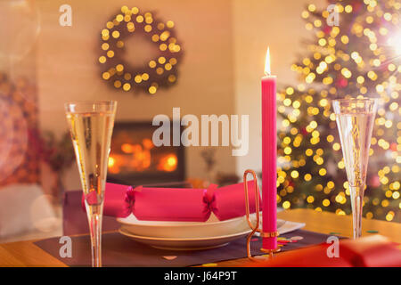 Champagne flute, candle and Christmas cracker on ambient table Stock Photo