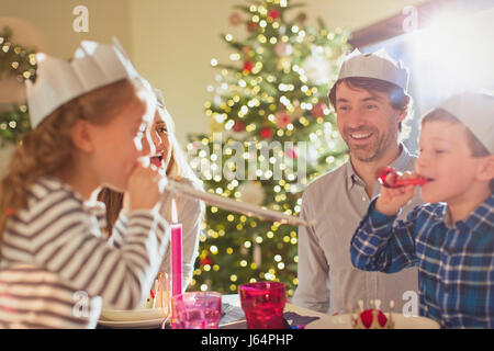 Family wearing paper crowns at Christmas dinner table Stock Photo