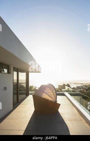 Covered patio chair on sunny modern luxury balcony under blue sky Stock Photo