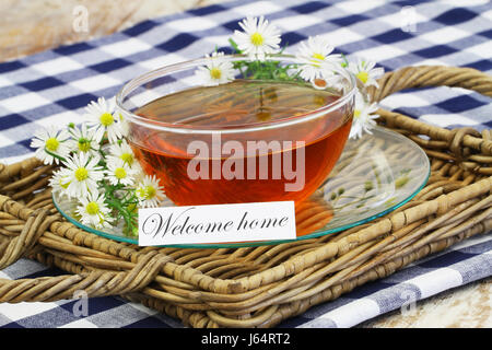 Welcome home card with cup of chamomile tea on wicker tray Stock Photo