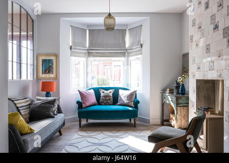 Large french metal salvaged windows in sitting room with Delft tiles around fireplace. The grey vintage sofa is from French Affair. the rug by Allegra Stock Photo