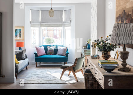 Open plan living place with long rustic wooden console table and vintage sofa upholstered in Ashton in Teal from Wemyss Stock Photo