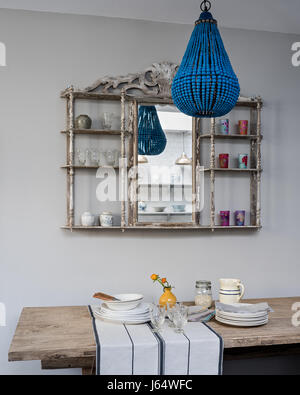 Blue turquoise chandelelier from Graham and Green in front of old bistro shelf with mirror panel. The provence wine glasses and selvedge napkins are b