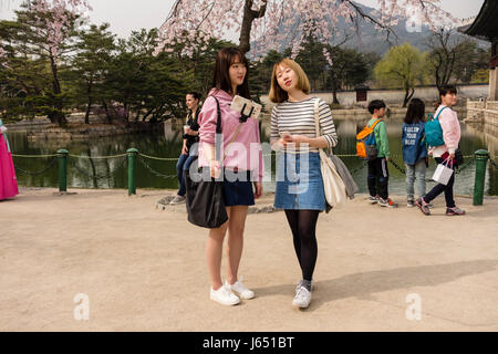 Two young female taking selfies by using a mobile phone & selfie stick at Gyeongbokgung Palace. Seoul, South Korea Stock Photo