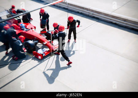 Pit crew replacing tires on formula one race car in pit lane Stock Photo