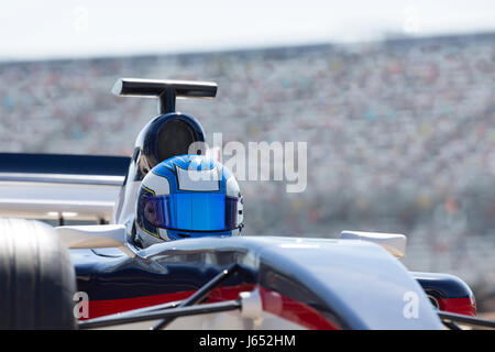 Formula one race car driver wearing helmet on sports track Stock Photo