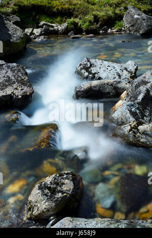 Long exposure causing motion blur of clear water flowing in a mountain stream through the Pass of Llanberis in snowdonia. Afon Nant Peris flows throug Stock Photo