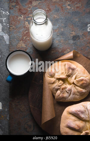 Ready-made khachapuri with cheese on parchment and milk in a bottle Stock Photo