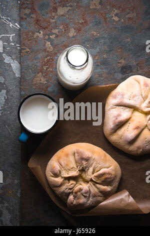 Ready-made khachapuri with cheese on parchment and milk in a bottle diagonal Stock Photo