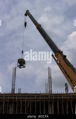Tower crane lift cement bucket up to top of building during construcion with cloudy sky background Stock Photo