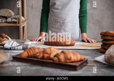 Cropped photo of young lady baker standing near bread Stock Photo