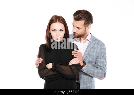 Image of offended young loving couple standing isolated over white background. Looking aside. Man ask for apologize. Stock Photo